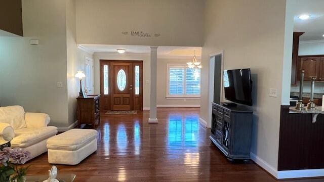 foyer featuring dark wood-style flooring, ornamental molding, baseboards, and ornate columns