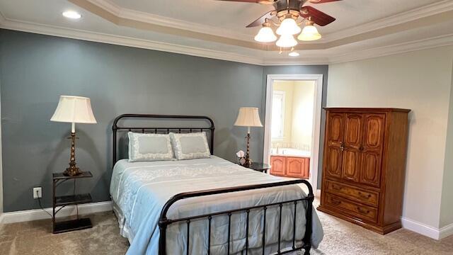 bedroom with light carpet, a raised ceiling, baseboards, and ornamental molding