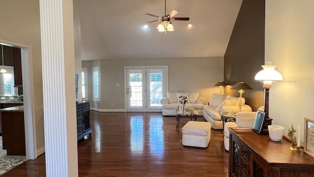 living area featuring high vaulted ceiling, ornate columns, dark wood-style flooring, a ceiling fan, and baseboards