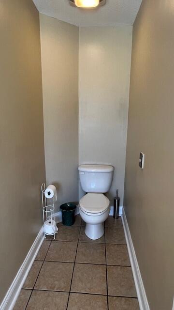 bathroom with toilet, baseboards, and tile patterned floors