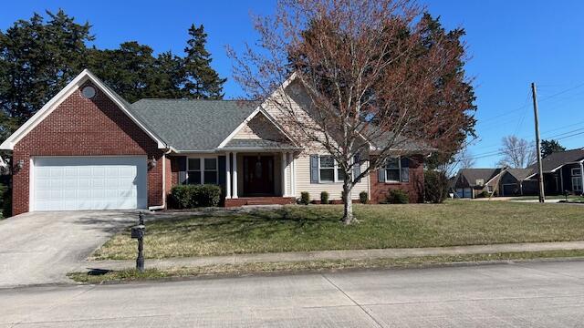 view of front of property featuring a front lawn, driveway, brick siding, and a garage