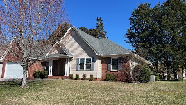 view of front of house with a front yard, brick siding, and a garage