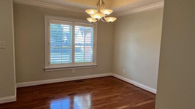 unfurnished room with an inviting chandelier, wood finished floors, baseboards, and ornamental molding