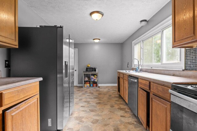 608 Parkview Dr, Chattanooga, TN 37411 - kitchen featuring a sink, stainless steel appliances, a textured ceiling, brown cabinetry, and light countertops