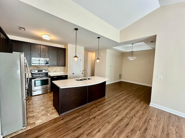 kitchen with a center island with sink, light hardwood / wood-style flooring, dark brown cabinets, and appliances with stainless steel finishes