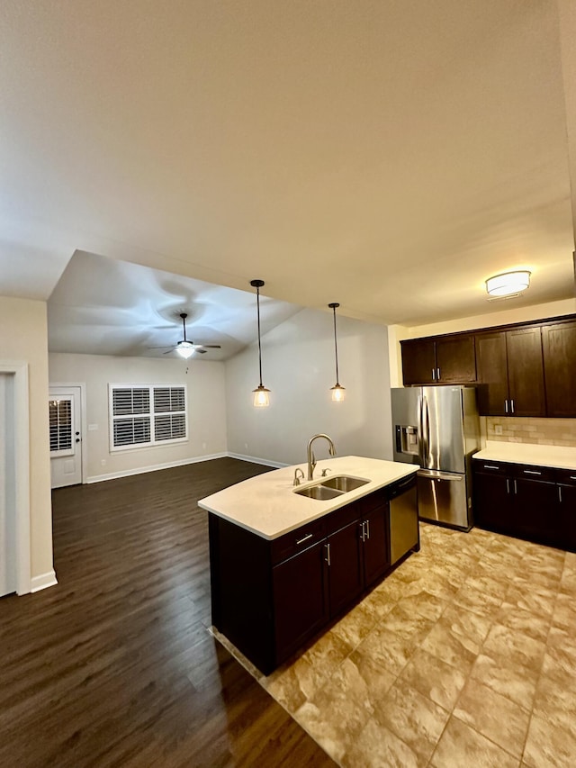 kitchen with appliances with stainless steel finishes, ceiling fan, a kitchen island with sink, sink, and decorative light fixtures