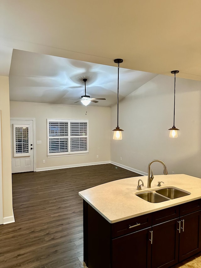 kitchen featuring dark wood-type flooring, sink, decorative light fixtures, and a center island with sink