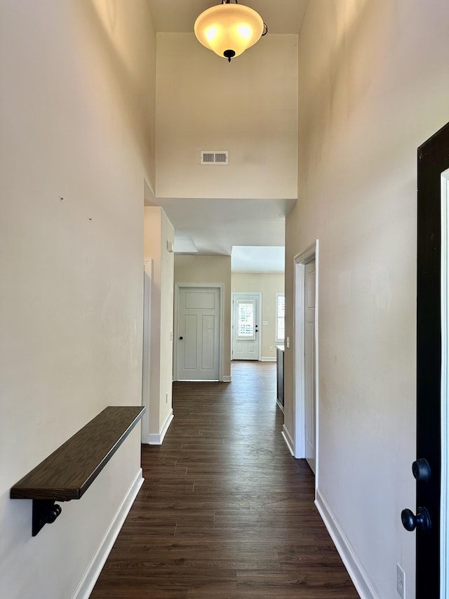 corridor featuring a high ceiling and dark hardwood / wood-style floors