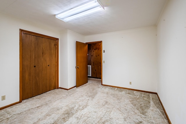 unfurnished bedroom featuring light carpet, a closet, and crown molding