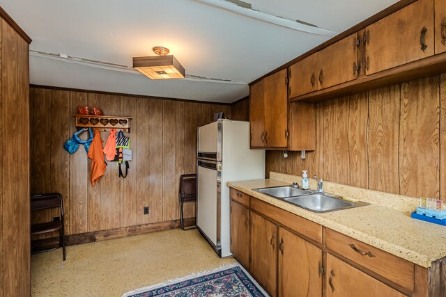 kitchen with white fridge, wooden walls, and sink