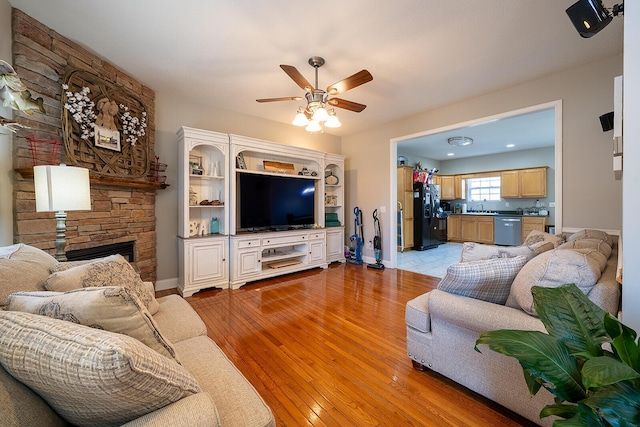 123 Carson Pl, Clinton, TN 37716 - living room featuring a ceiling fan, light wood-type flooring, a stone fireplace, and baseboards