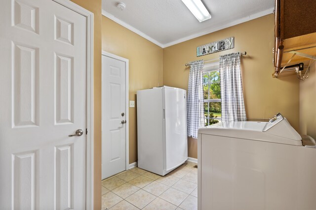 washroom featuring light tile patterned floors, washing machine and dryer, crown molding, baseboards, and cabinet space