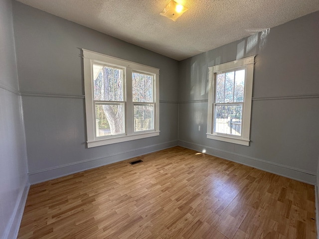 unfurnished room featuring light hardwood / wood-style floors and a textured ceiling