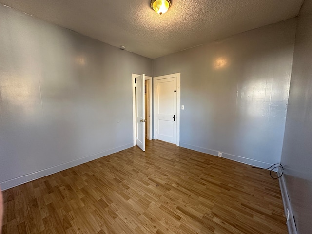 empty room with wood-type flooring and a textured ceiling