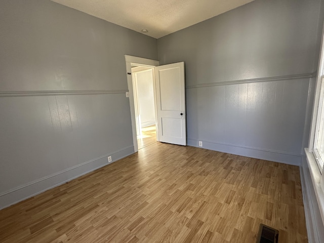 empty room with light hardwood / wood-style flooring and a textured ceiling