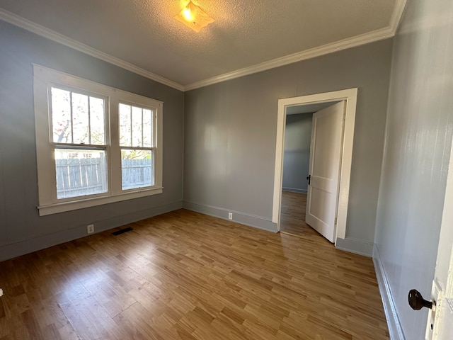 empty room featuring hardwood / wood-style floors, ornamental molding, and a textured ceiling