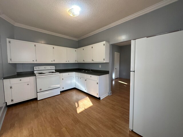 kitchen with white appliances, a textured ceiling, crown molding, white cabinets, and hardwood / wood-style floors