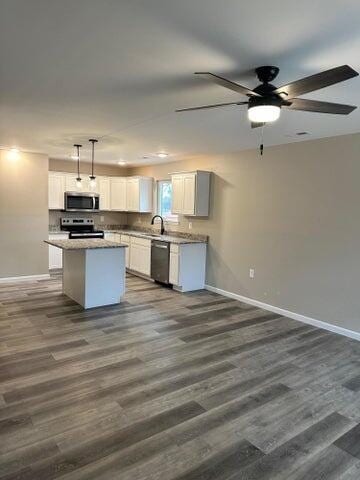 kitchen with pendant lighting, white cabinetry, stainless steel appliances, a kitchen island, and dark hardwood / wood-style flooring