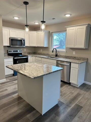 kitchen featuring white cabinetry, pendant lighting, stainless steel appliances, and a kitchen island