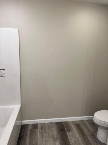 bathroom featuring a tub, hardwood / wood-style floors, and toilet