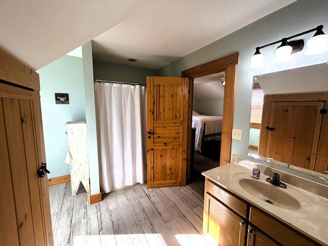 bathroom with vanity, lofted ceiling, and hardwood / wood-style flooring