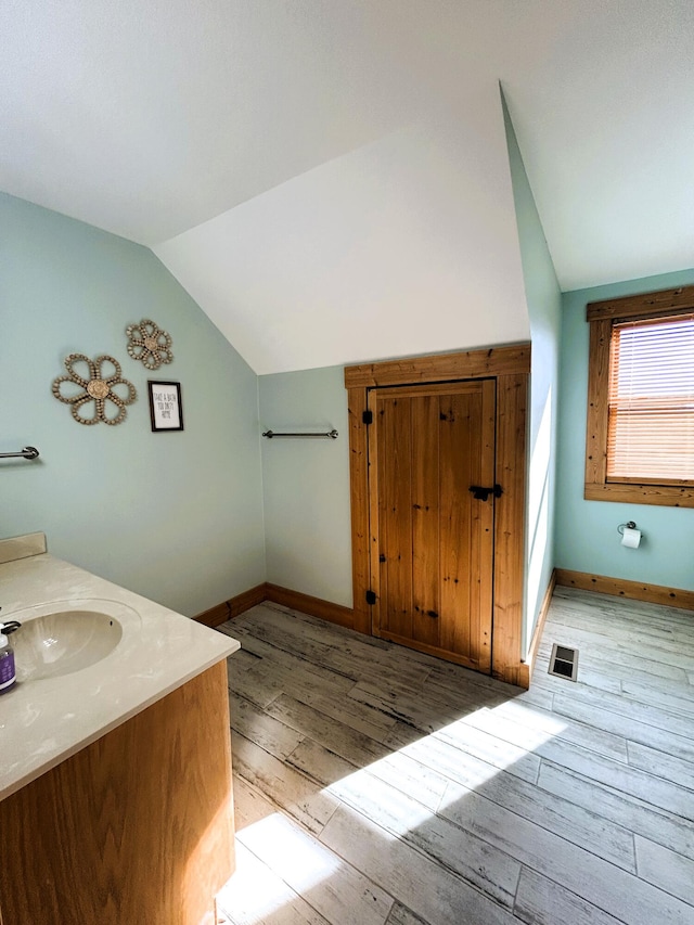 bathroom with wood-type flooring, vanity, and vaulted ceiling