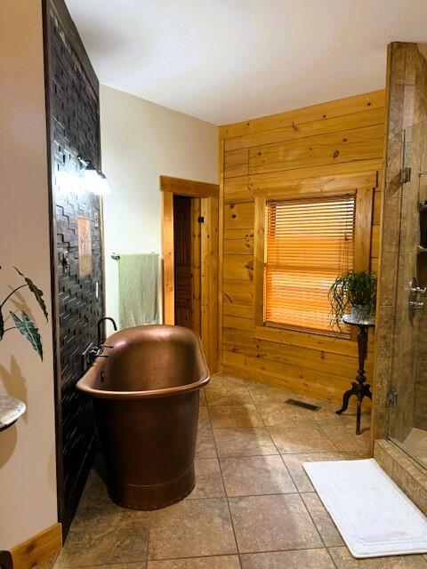 bathroom featuring plus walk in shower, tile patterned floors, and wood walls