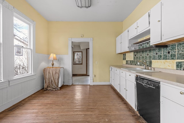 kitchen featuring tasteful backsplash, sink, black dishwasher, light hardwood / wood-style floors, and white cabinetry