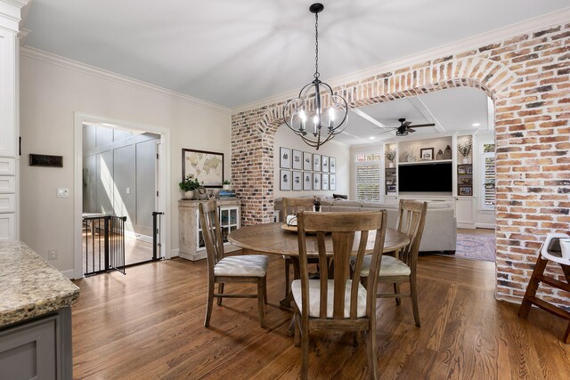 dining area featuring built in shelves, crown molding, ceiling fan with notable chandelier, and hardwood / wood-style flooring