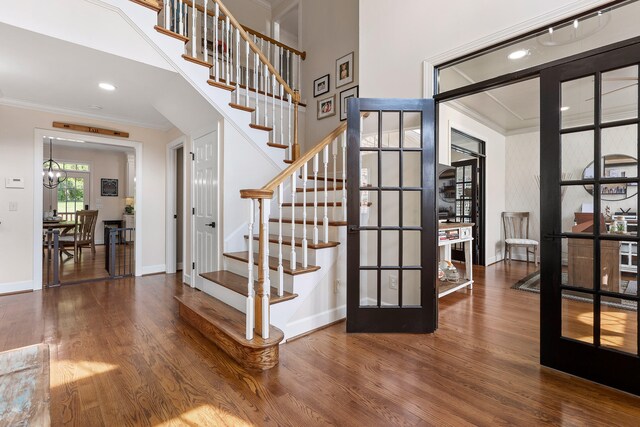 stairs featuring a chandelier, crown molding, french doors, and wood-type flooring