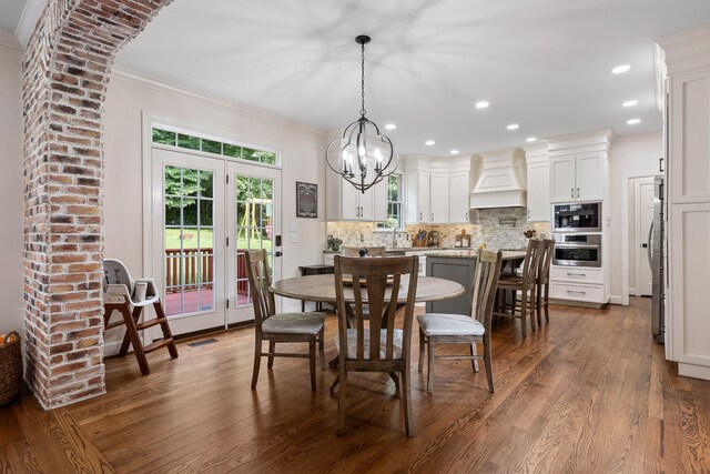 dining space with french doors, dark hardwood / wood-style flooring, a notable chandelier, and ornamental molding