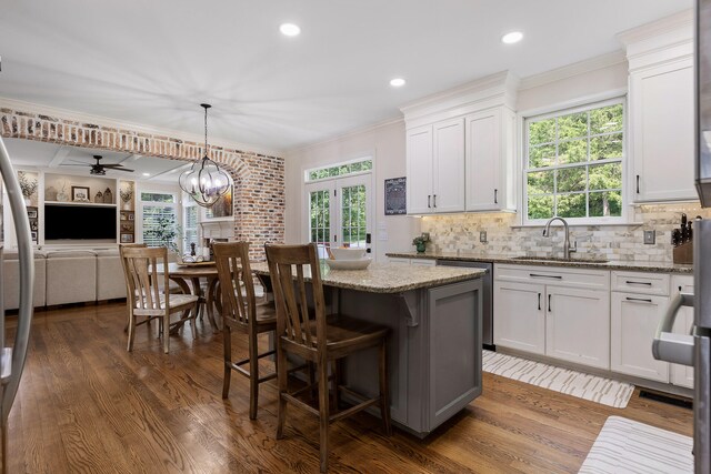 kitchen with light stone countertops, ceiling fan with notable chandelier, white cabinetry, and hanging light fixtures