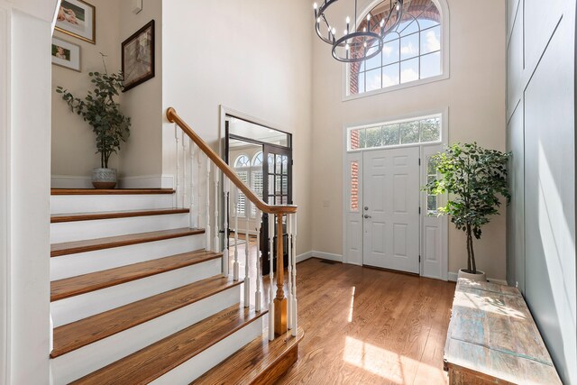 foyer entrance with light hardwood / wood-style flooring, a chandelier, and a high ceiling