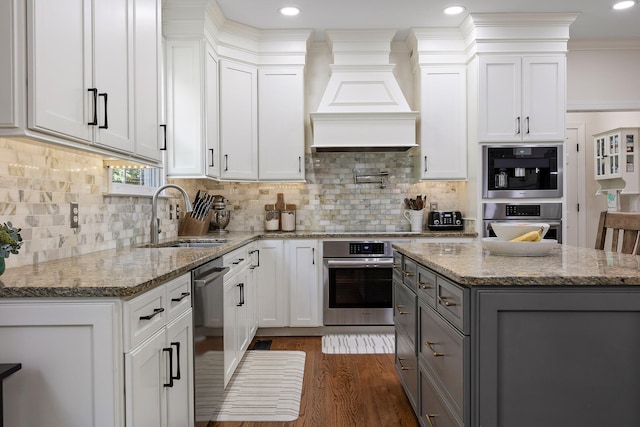 kitchen with light stone counters, gray cabinetry, custom exhaust hood, sink, and white cabinets