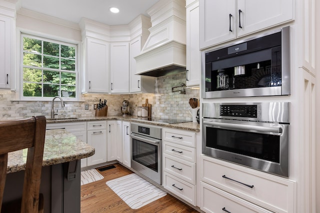 kitchen with light stone countertops, white cabinetry, sink, stainless steel appliances, and tasteful backsplash