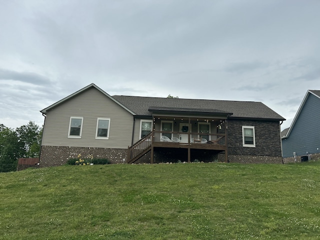 rear view of house with roof with shingles and a yard