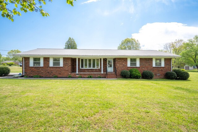 ranch-style home featuring brick siding, a front lawn, and metal roof