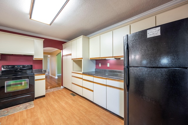 kitchen featuring crown molding, arched walkways, light wood-type flooring, visible vents, and black appliances