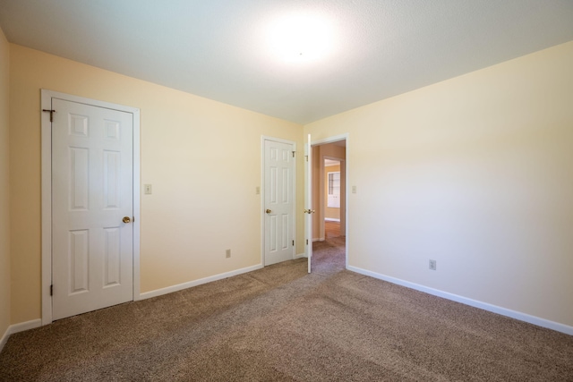 unfurnished bedroom with carpet floors and baseboards