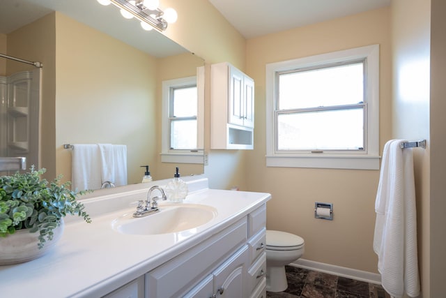 full bathroom with walk in shower, vanity, toilet, baseboards, and stone finish flooring