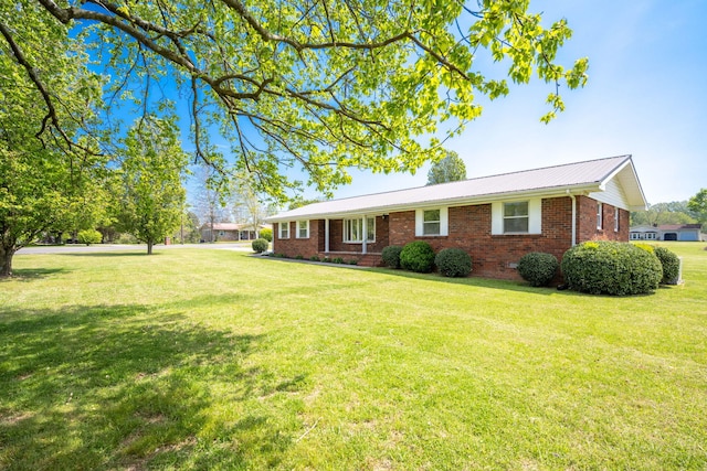 view of front of home featuring a front yard, metal roof, and brick siding