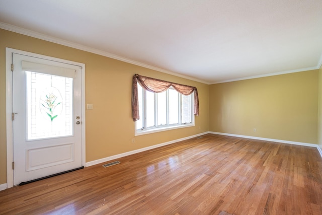 entryway with light wood-style floors, baseboards, ornamental molding, and visible vents