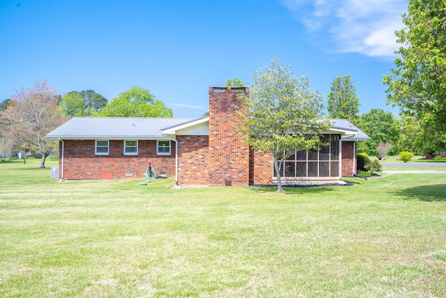rear view of house with a lawn, a sunroom, and a chimney