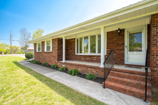single story home with brick siding, a front yard, and a porch
