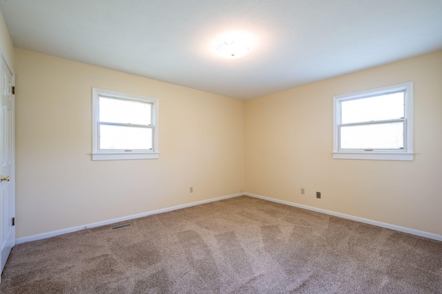 unfurnished room with baseboards, plenty of natural light, carpet flooring, and visible vents