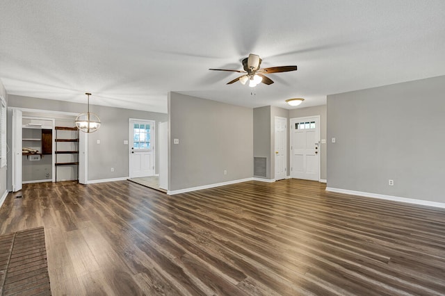 unfurnished living room with ceiling fan with notable chandelier and dark hardwood / wood-style flooring