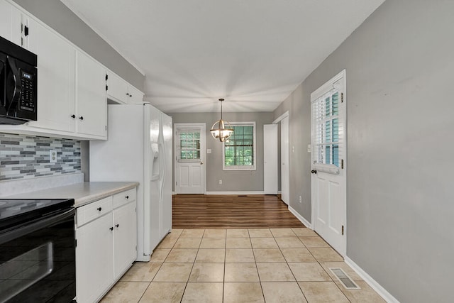 kitchen featuring white cabinetry, hanging light fixtures, an inviting chandelier, light hardwood / wood-style floors, and black appliances