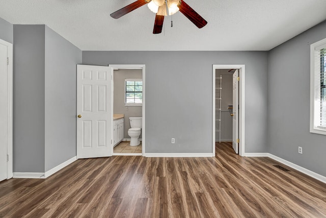 unfurnished bedroom featuring a spacious closet, ceiling fan, and dark hardwood / wood-style floors