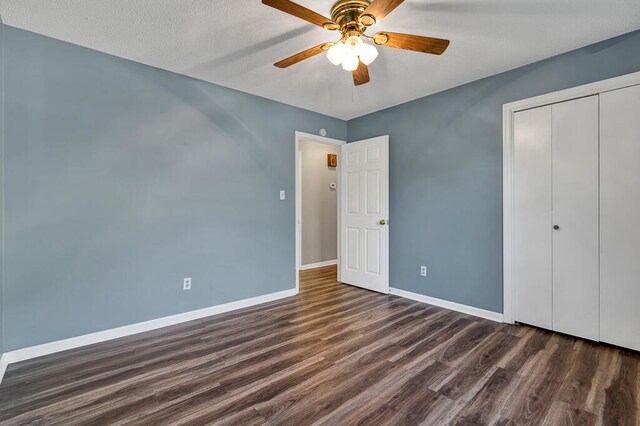 unfurnished bedroom featuring a textured ceiling, ceiling fan, dark wood-type flooring, and a closet