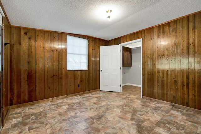 empty room featuring a textured ceiling and wooden walls